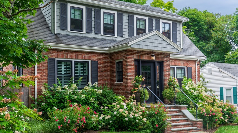 A two-story brick house with black window shutters