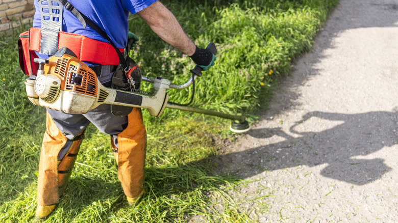 Lawn care professional weed eating along the walkway