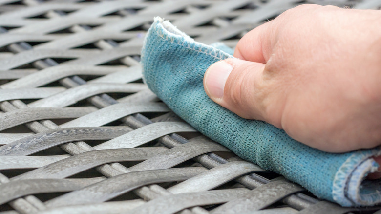 Person wiping patio furniture with cloth