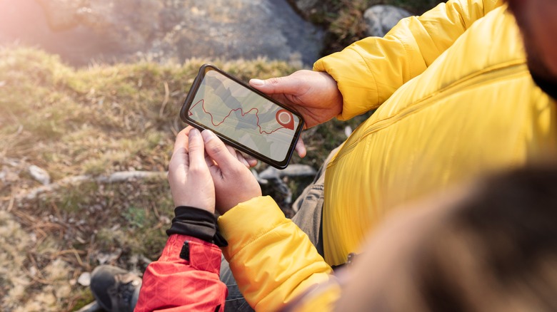 Two hikers hold a phone with navigation