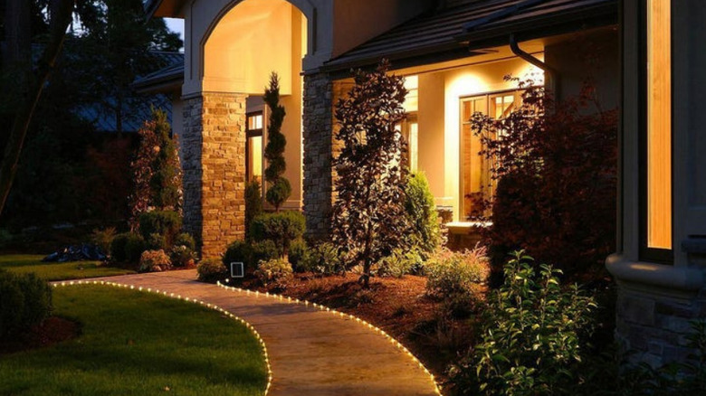 Rope lights running along the side of a walkway leading to a home