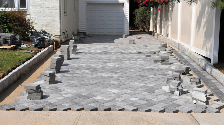 A concrete paver driveway being laid with several stacks of pavers