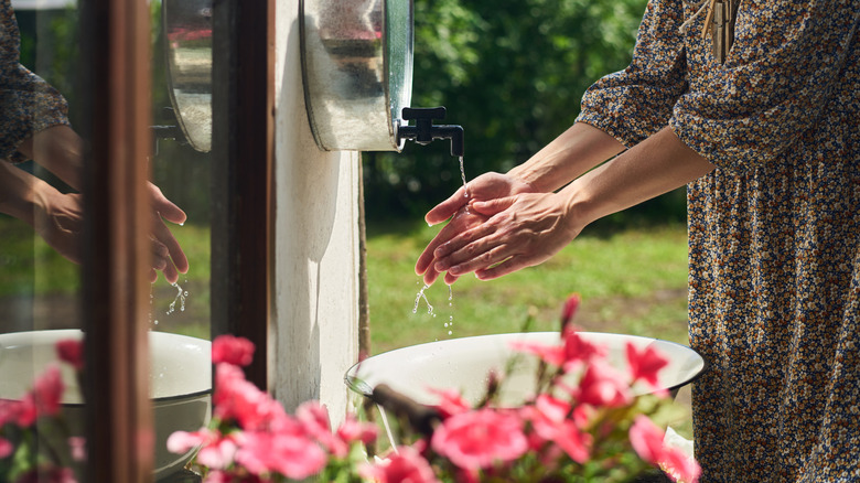 person washing hands in a garden sink