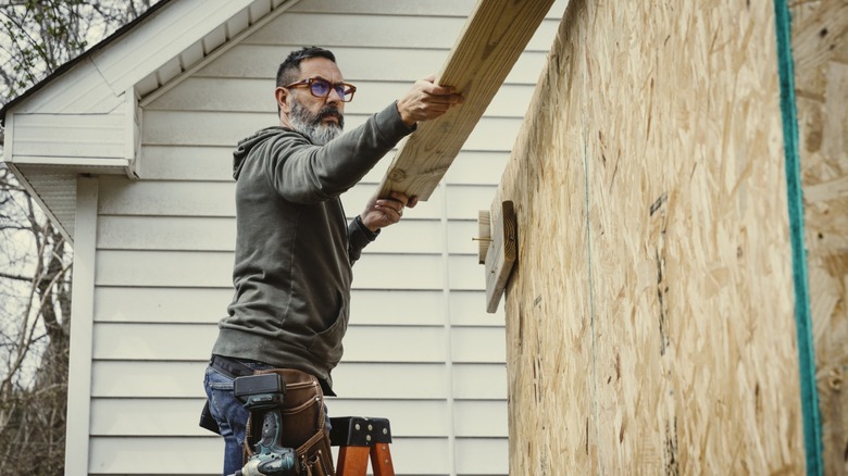 A man on a ladder building a structure