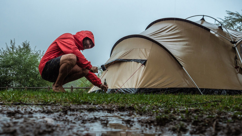 Person pitching a tent in the rain