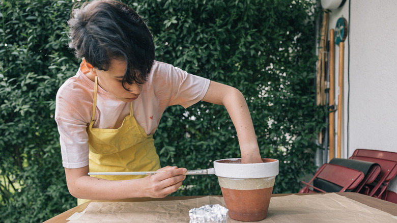 Person painting a terracotta pot