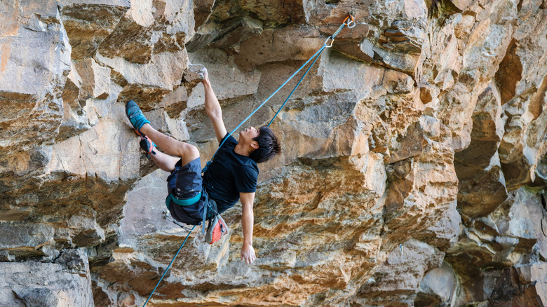Rock climber hanging from handhold