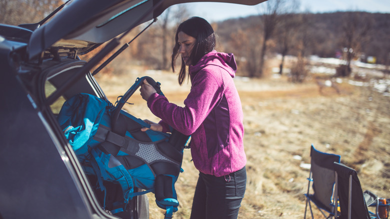 Woman taking backpack out of car as she gets ready to hike