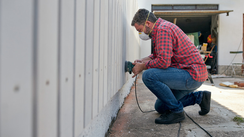 man sanding fence picket