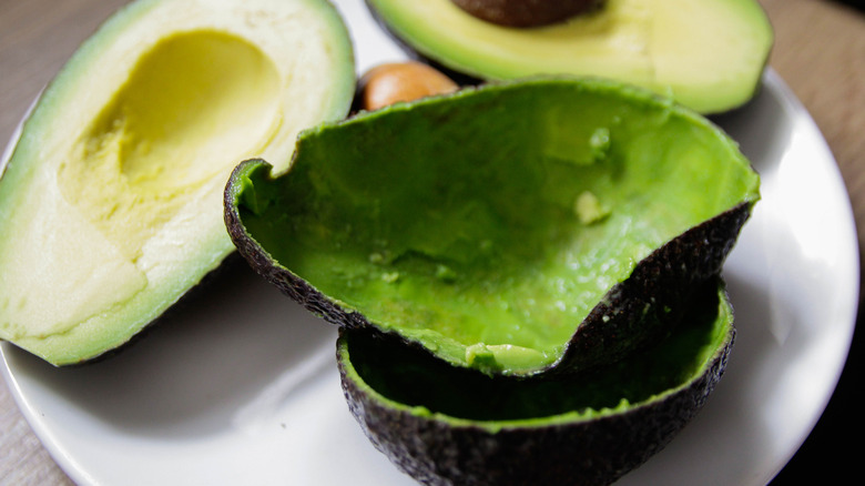 avocado skins or peels, with avocados in the background