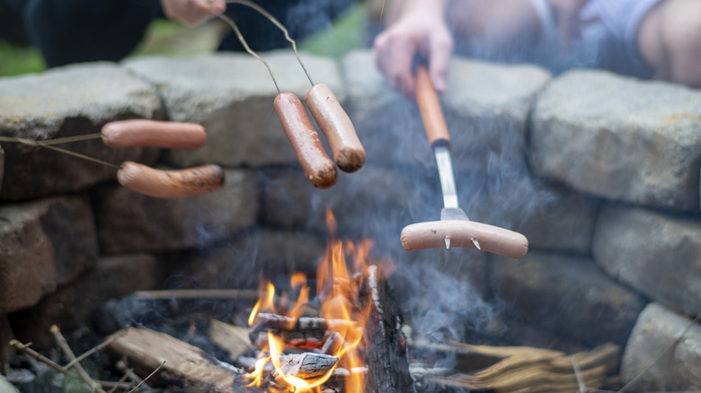 Campers roasting hot dogs over a fire