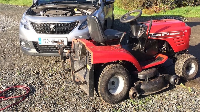 Lawn mower, car, and battery cables on the ground