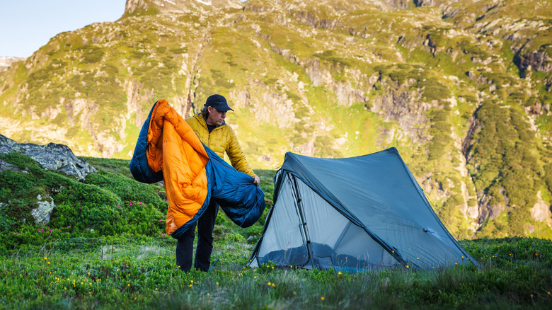 Person unpacking sleeping bag outside tent