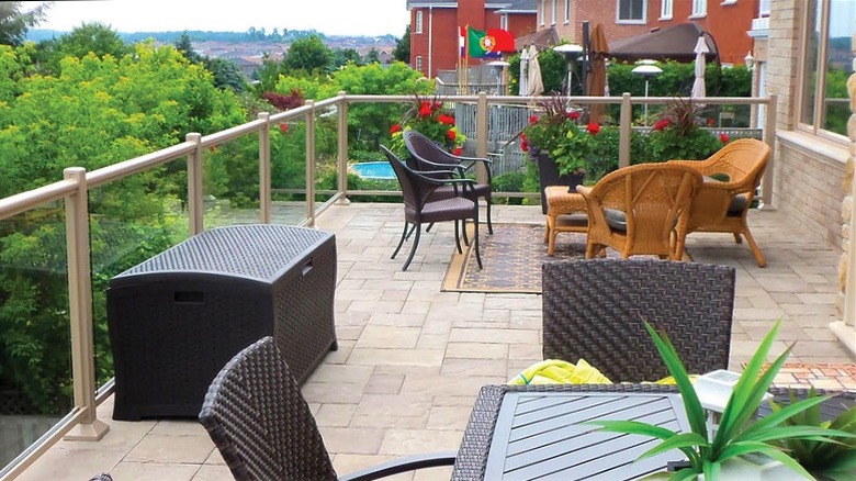A deck overlooking beautiful greenery with pavers installed and furniture on top