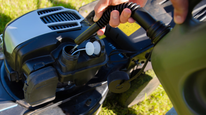 Person refilling a mower's gas tank