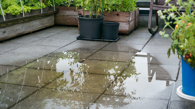 Concrete tiled patio flooded with pooling water that has nowhere to drain.
