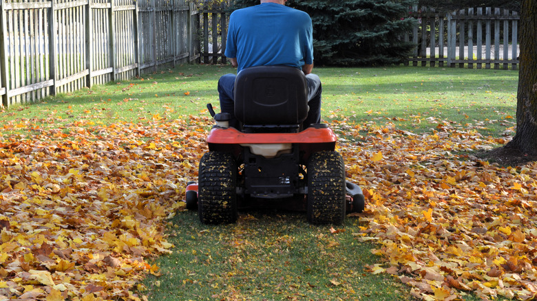 man mowing with a new looking riding mower in fall, mulching the autumn leaves
