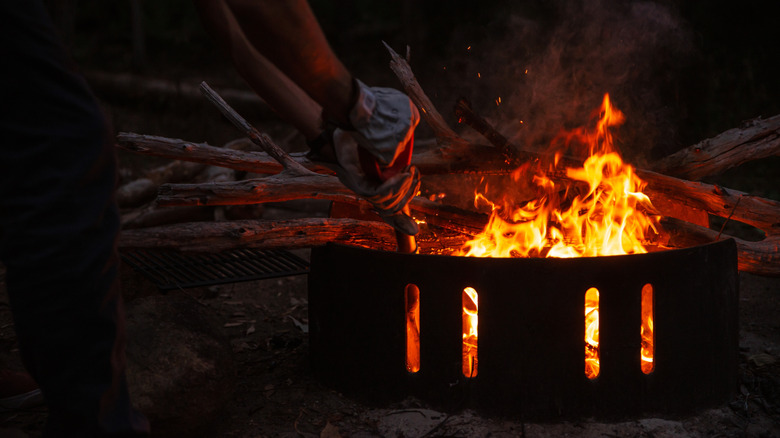 man tends a fire while camping