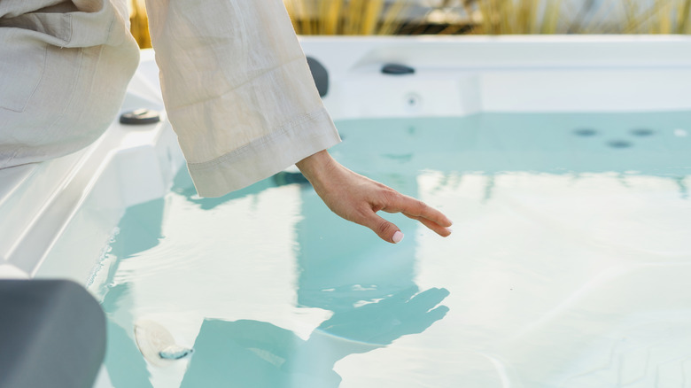 woman in robe testing hot tub water