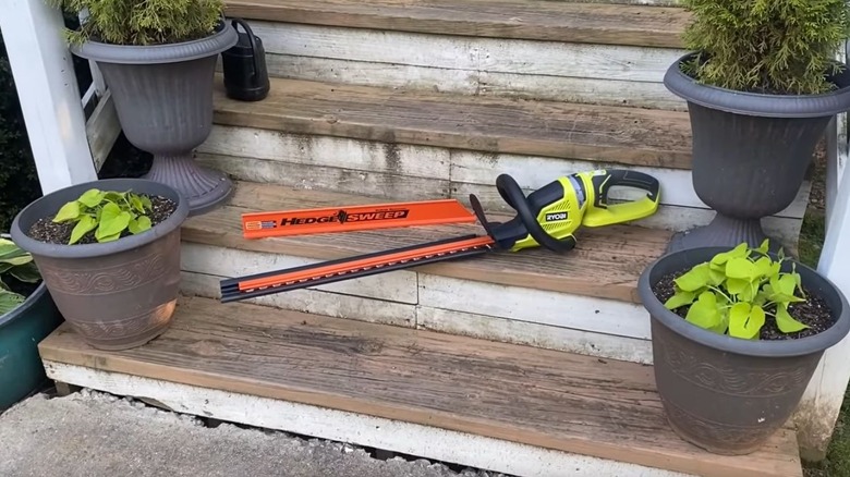 Ryobi's 22-inch Cordless Hedge Trimmer sitting on the front porch steps