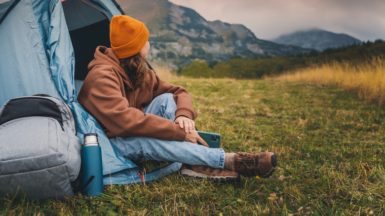 girl sitting in door to tent looking at mountains