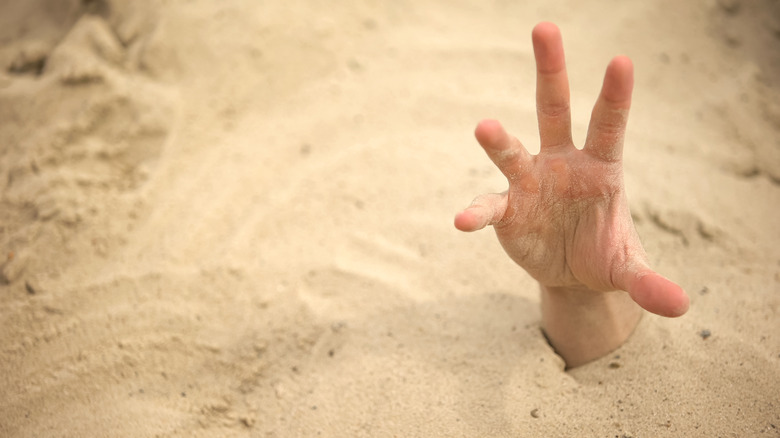 Hand reaching out of the sand