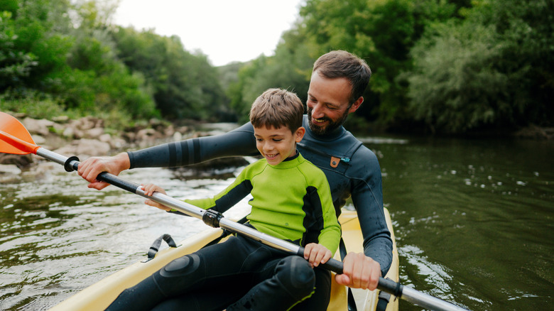 Father and son wearing wet suits while kayaking