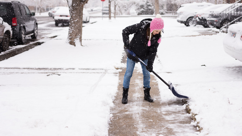 Woman clears snow on a sidewalk