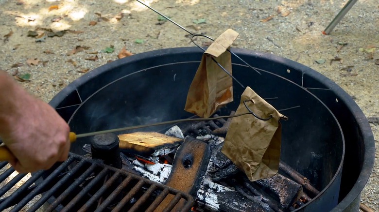 Cooking bacon and eggs in a brown paper bag over a campfire
