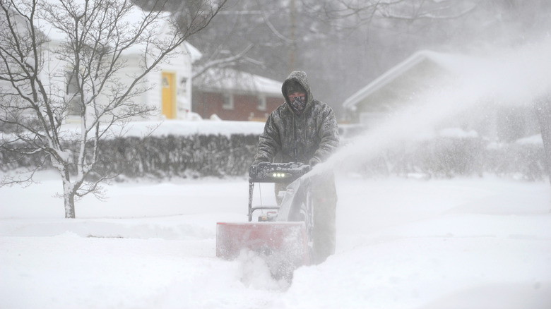 Clearing snow from sidewalk with snow blower