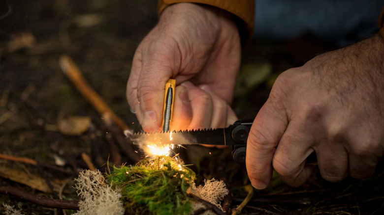 Man starts a fire using the ferro tool and saw on the Leatherman Signal