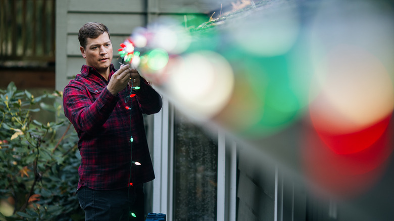 Man hanging colorful holiday lights