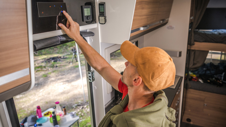 Man adjusting the temperature controls inside an RV