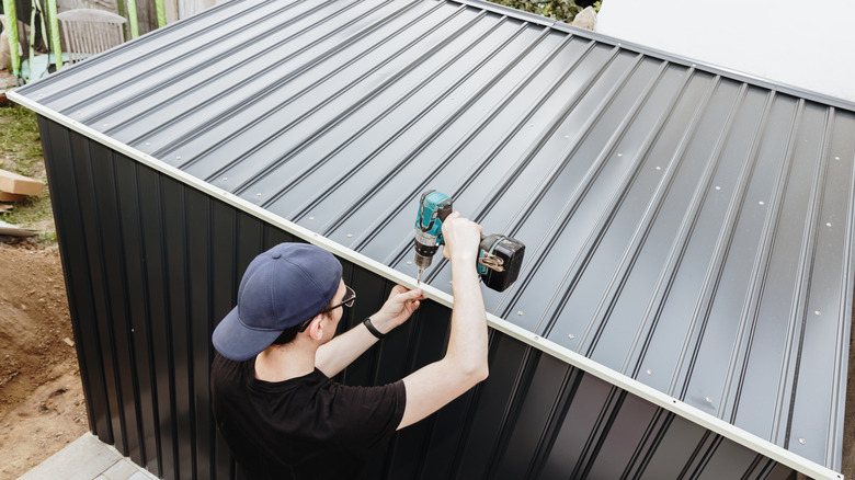Man assembles a metal shed