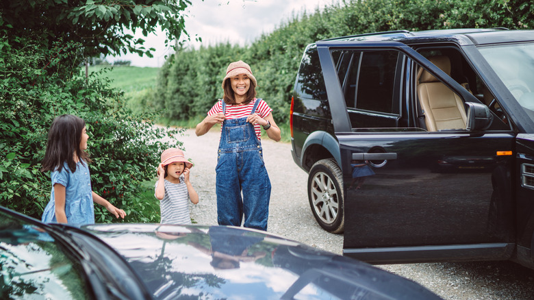 Woman and two young girls outside an SUV with the door open