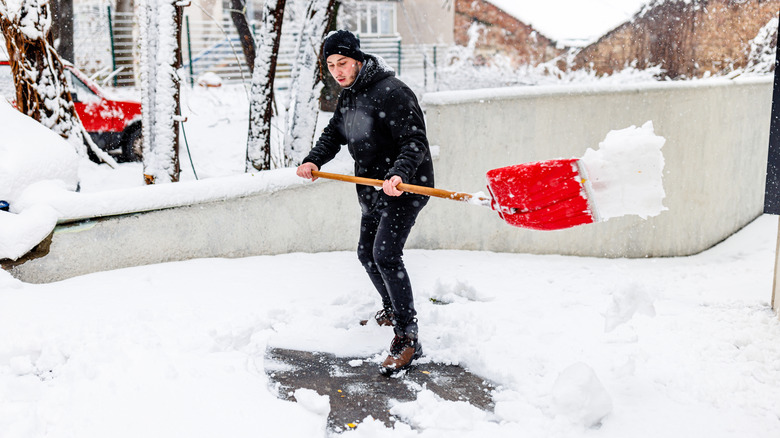 Snow flies off shovel as man shovels
