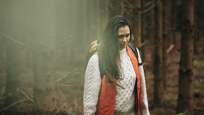 a woman walks alone in the forest