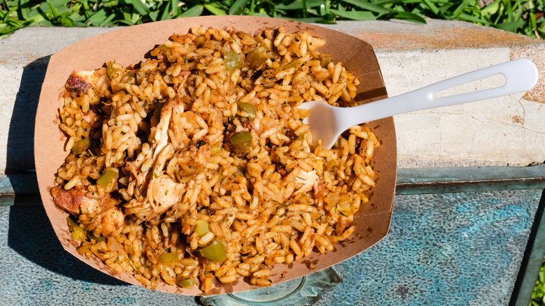 A paper bowl of jambalaya with a plastic fork