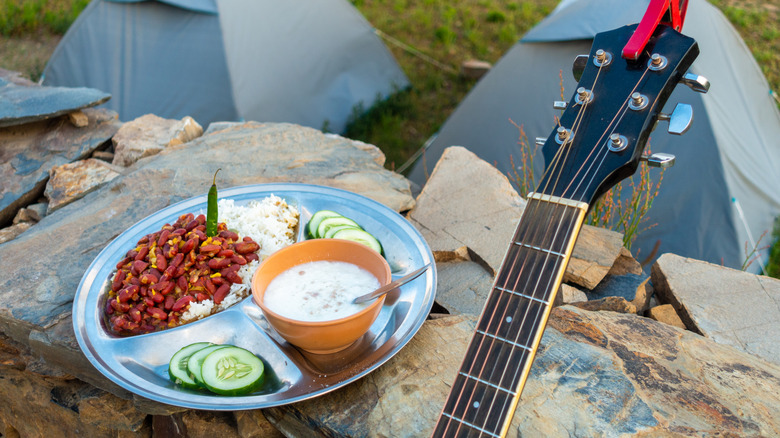 A plate of red beans and rice next to two tents and a guitar