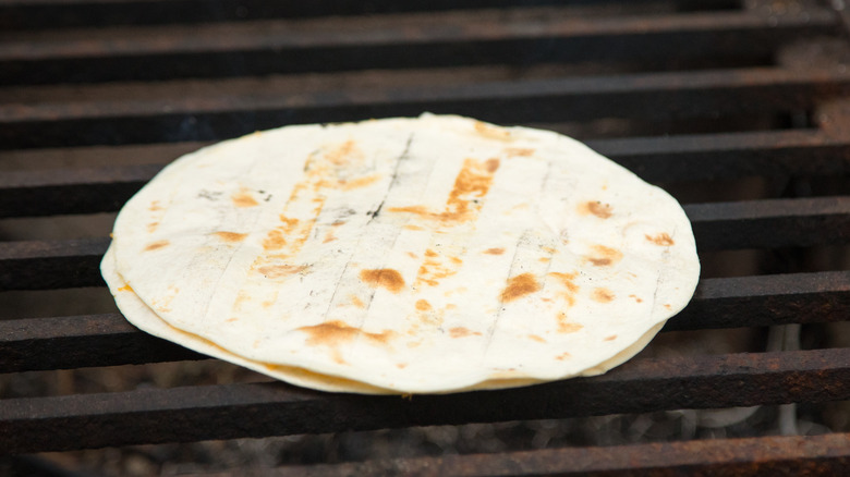 A cheese quesadillas cooking on a grate over charcoal