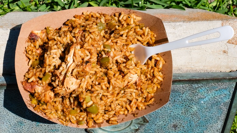 A paper bowl of jambalaya with a plastic fork