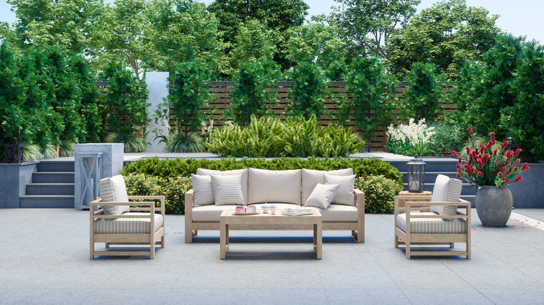 A patio with modern, deep-cushioned, wooden furniture