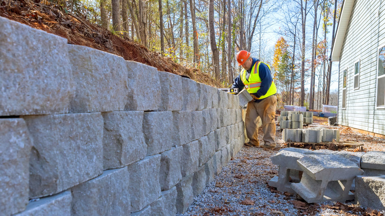 A construction working building a retaining wall