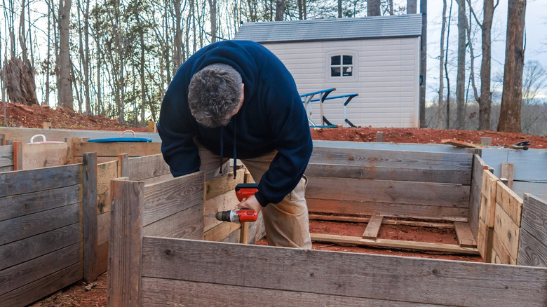 A person building wooden raised beds