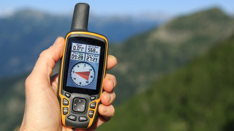Close-up of a hiker's hand holding a dedicated GPS device