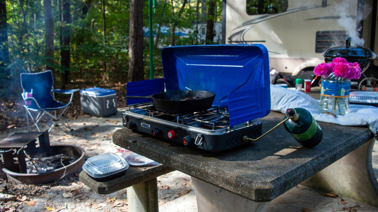 A two-burner camp stove being used for cooking