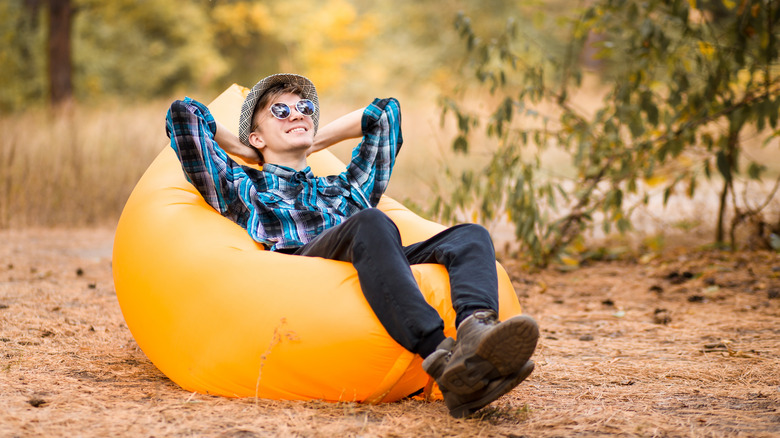 A man reclining outside on a yellow inflatable chair