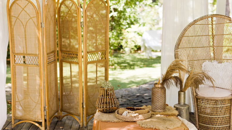 backyard patio area with rattan privacy screen and a wicker fan back chair