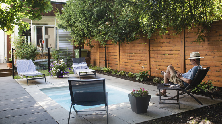 A small outdoor space with seats and a pool, man sitting on chair
