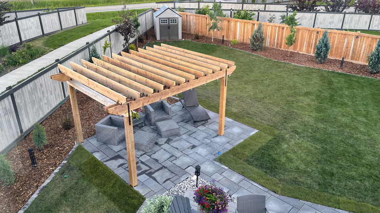 A pergola above a lounge area in a yard